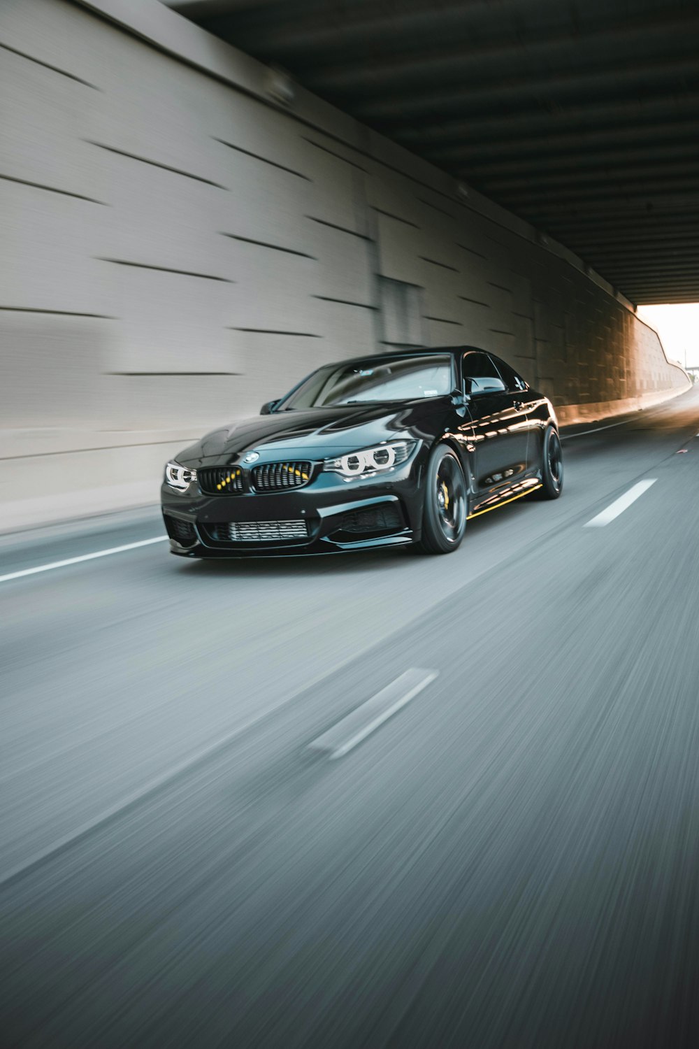 a black car driving down a highway next to a tunnel