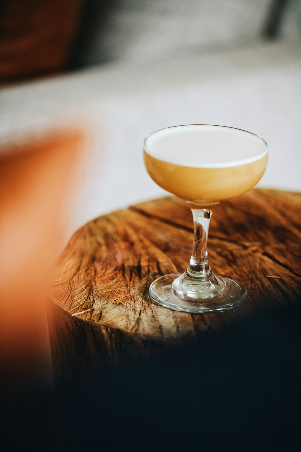 a glass of alcohol sitting on top of a wooden table