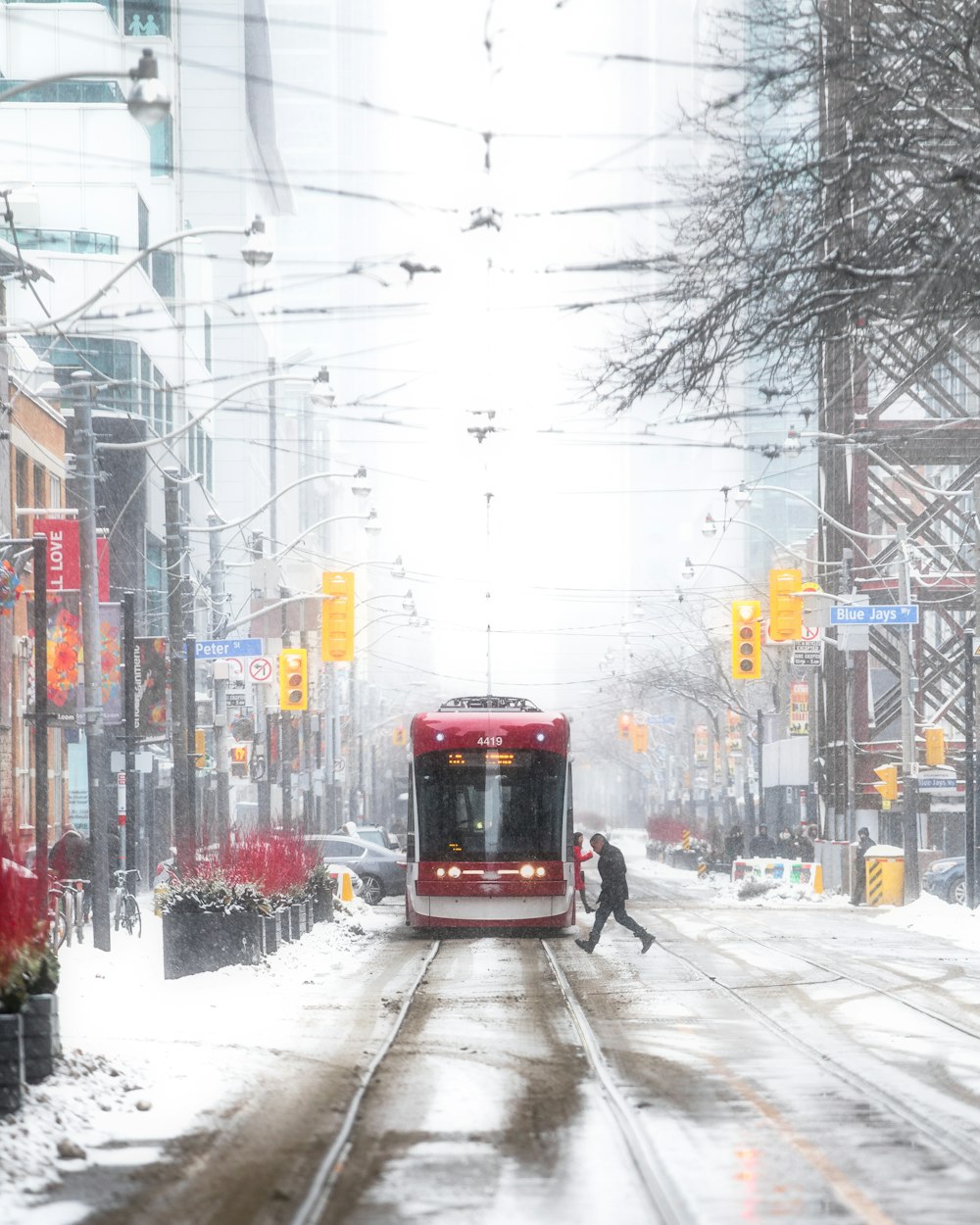 a red bus driving down a snow covered street