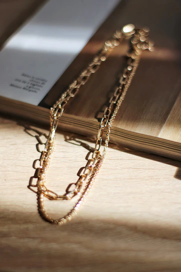 Close-up of a rose gold necklace resting delicately on blush pink fabric, sparkling softly in natural light.
