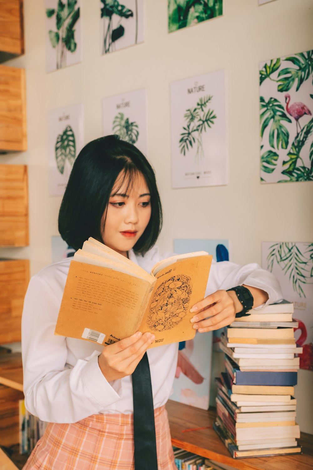 a woman reading a book in front of a stack of books