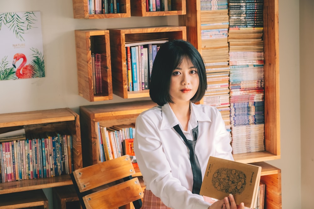 a woman in a white shirt and tie holding a book