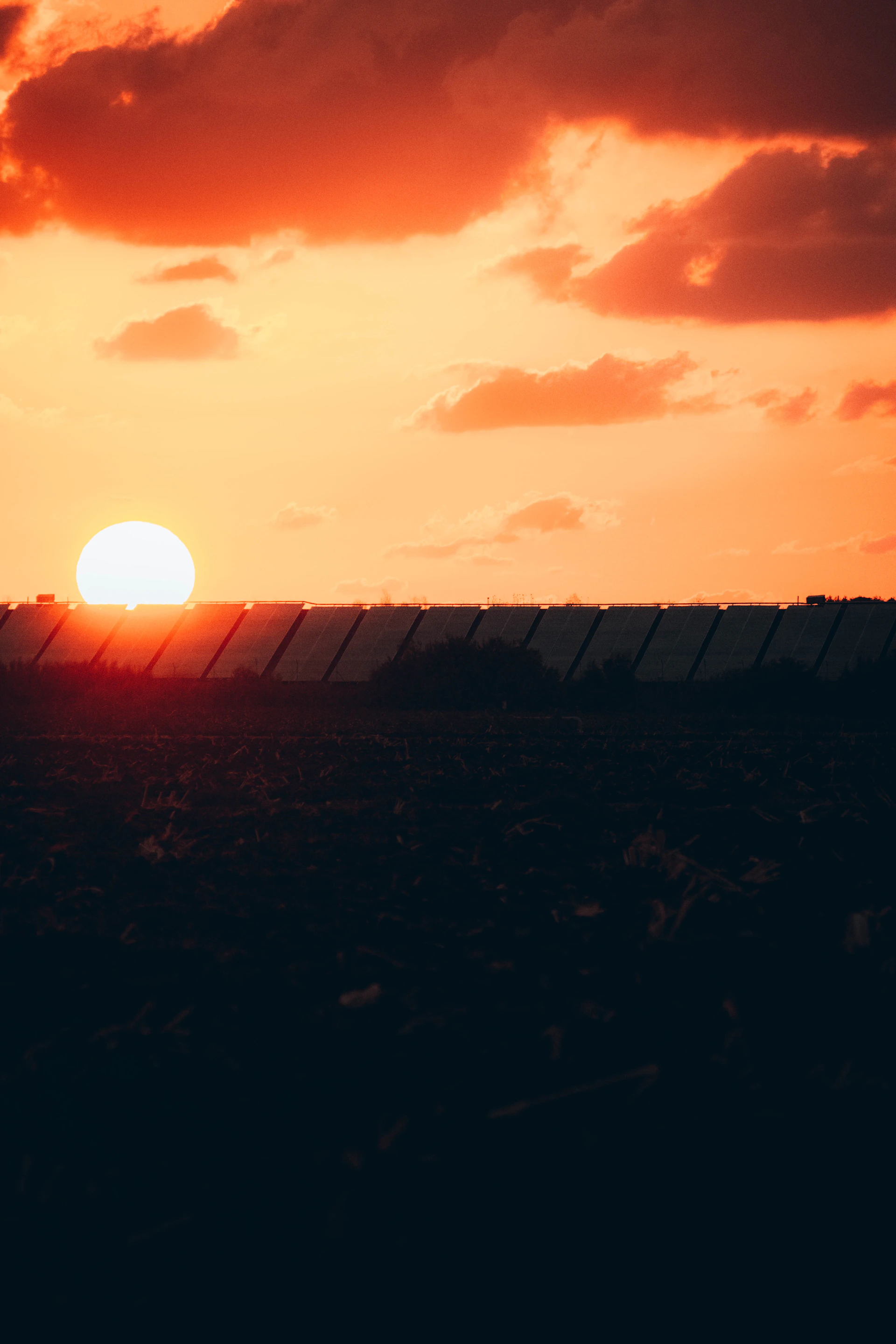 the sun is setting over the horizon of a field