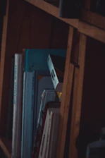 A shadowy bookshelf filled with leather-bound books, their spines glowing softly under low light.