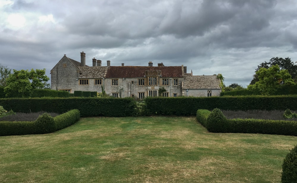 a large house surrounded by hedges on a cloudy day