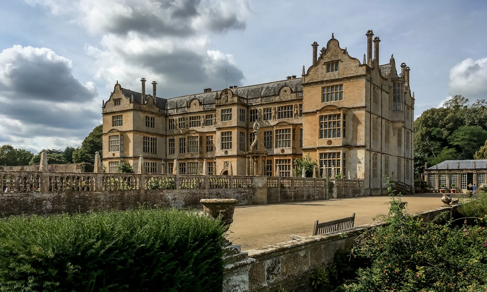 a large building with a stone wall and a bench in front of it