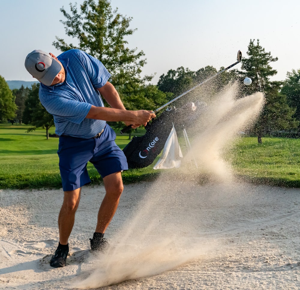 a man hitting sand with a golf club