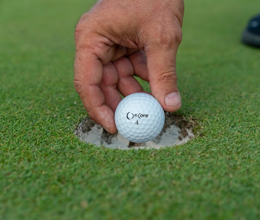 a person putting a golf ball into a hole