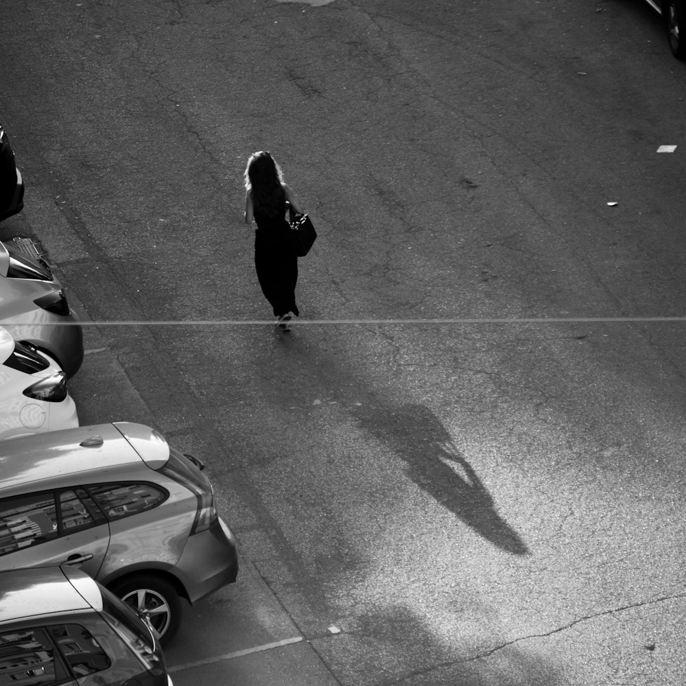 a woman walking down a street next to parked cars