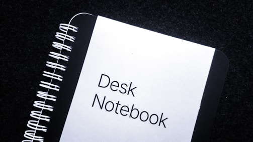 Close-up of a spiral notebook with a red cover and crisp white pages on a wooden desk