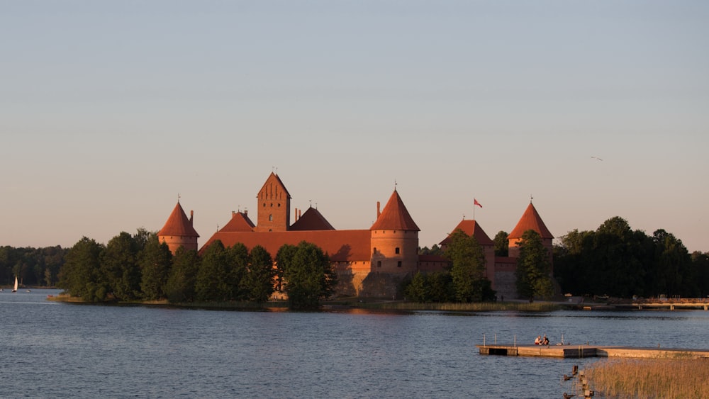 a castle sitting on top of a lake next to a forest