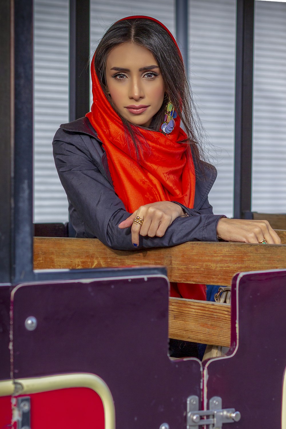 Une femme en foulard rouge appuyée sur un banc en bois