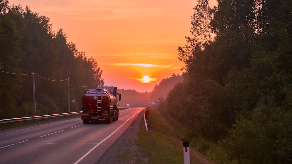 a semi truck driving down a road at sunset