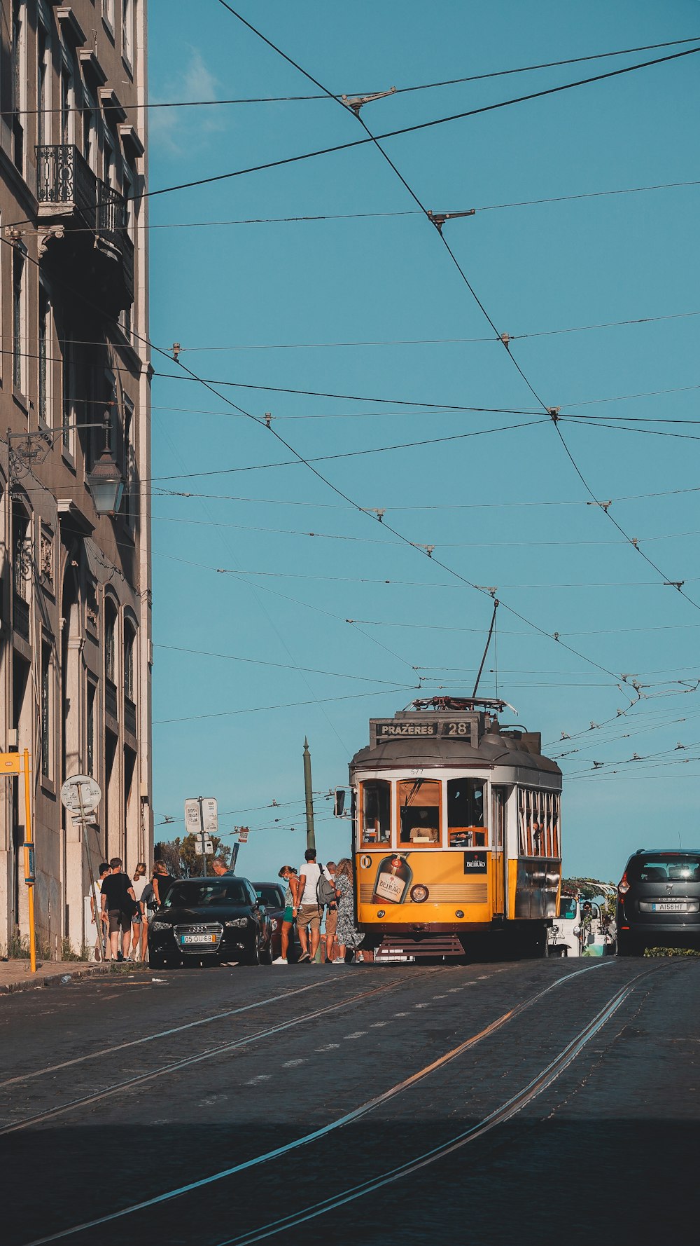 a yellow trolley car traveling down a street next to tall buildings