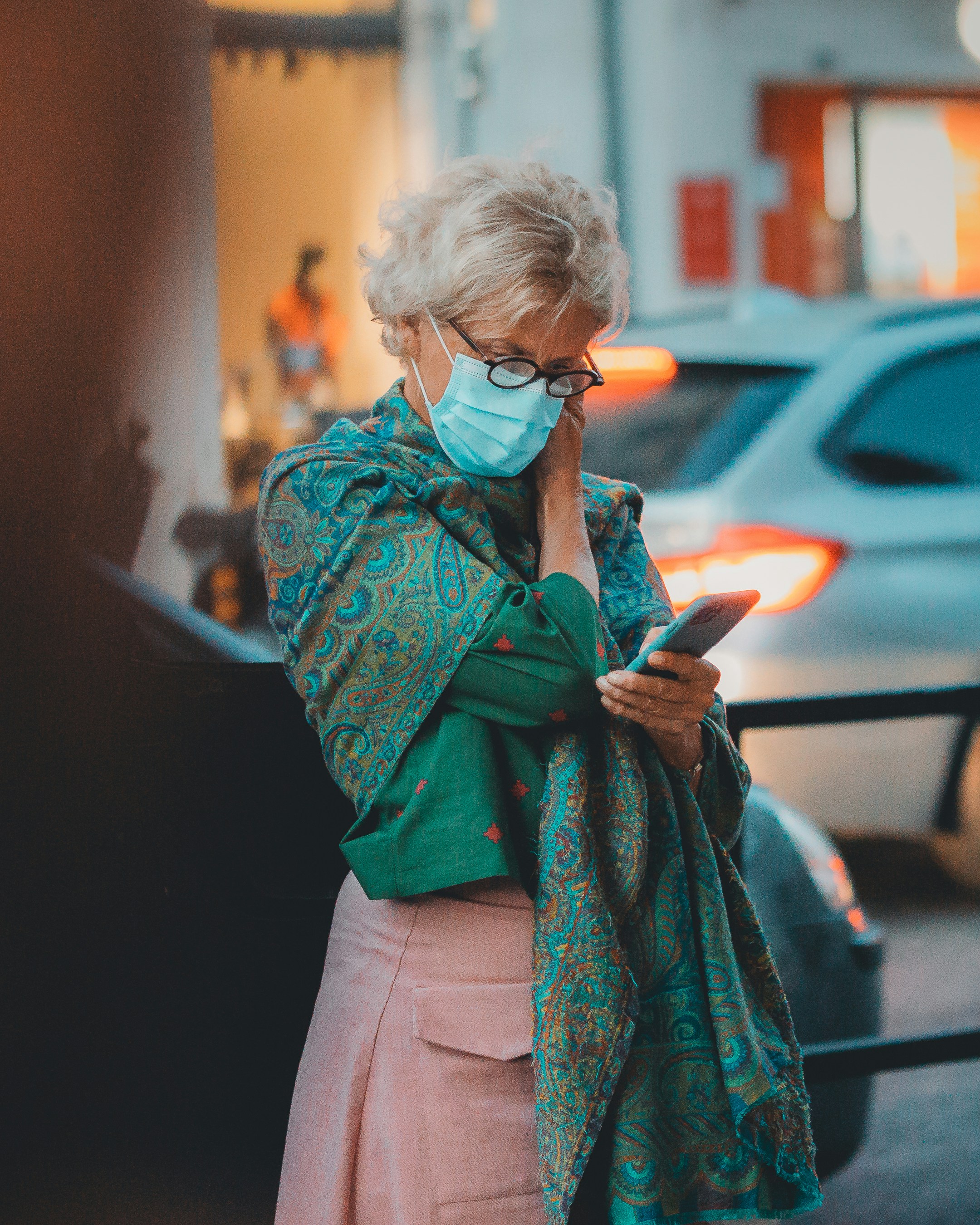 Une femme portant un masque facial tout en regardant son téléphone portable