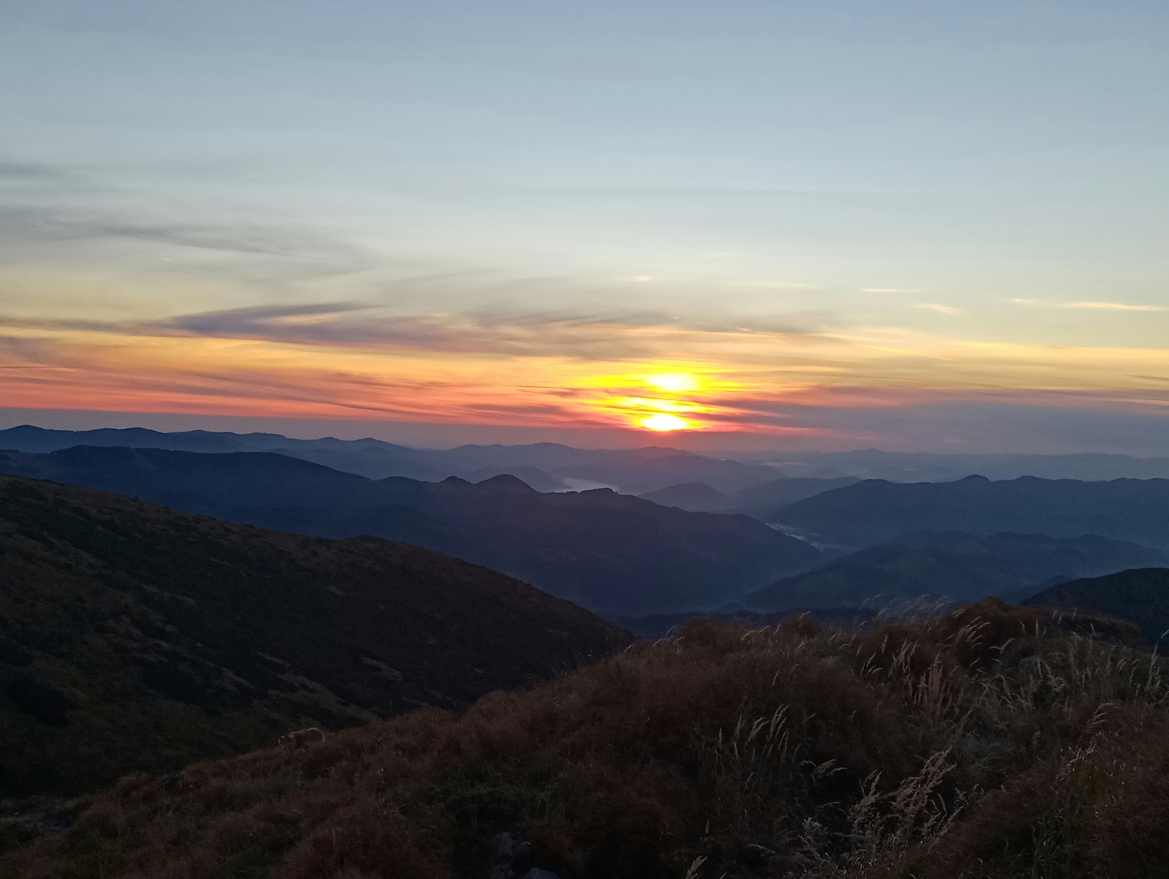 the sun is setting over a mountain range
