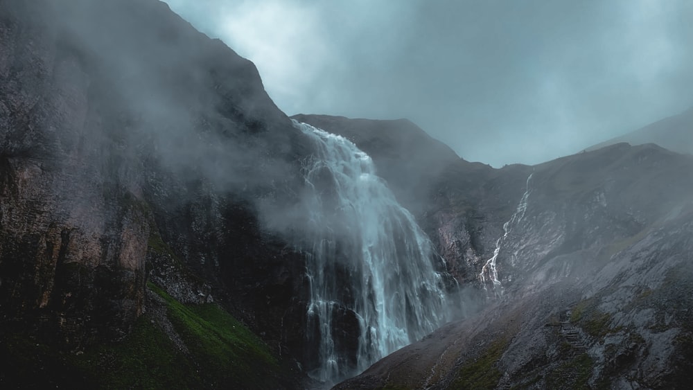 a very tall waterfall in the middle of a mountain