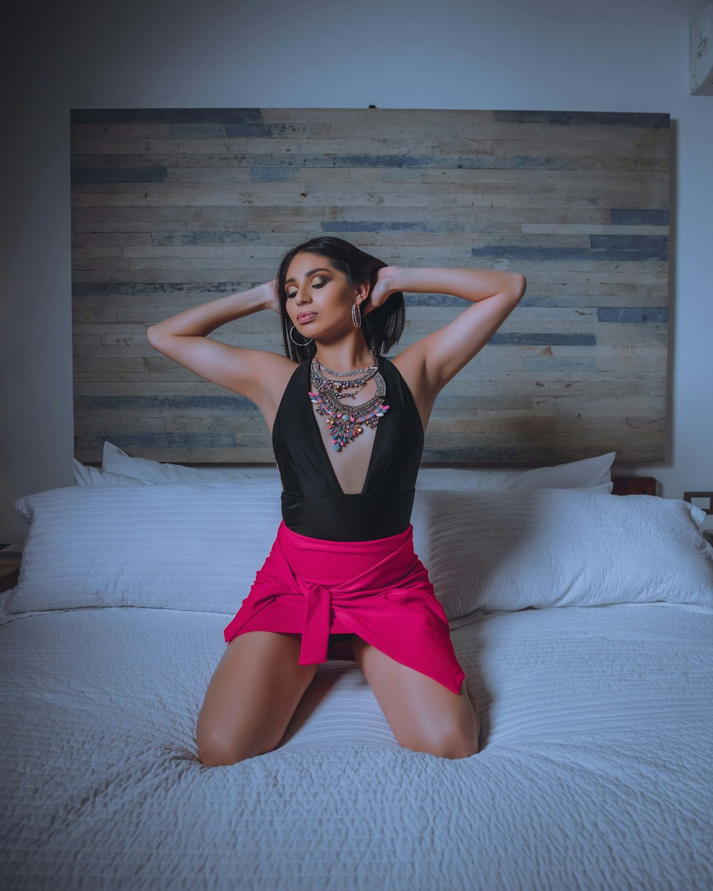 a woman in a black top and pink skirt sitting on a bed