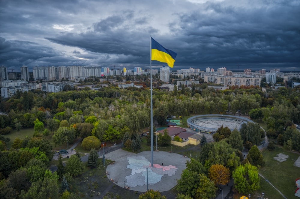 a cloudy sky over a park with a yellow and blue flag