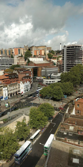 A vibrant cityscape showing modern apartments and busy streets with buses and cars.