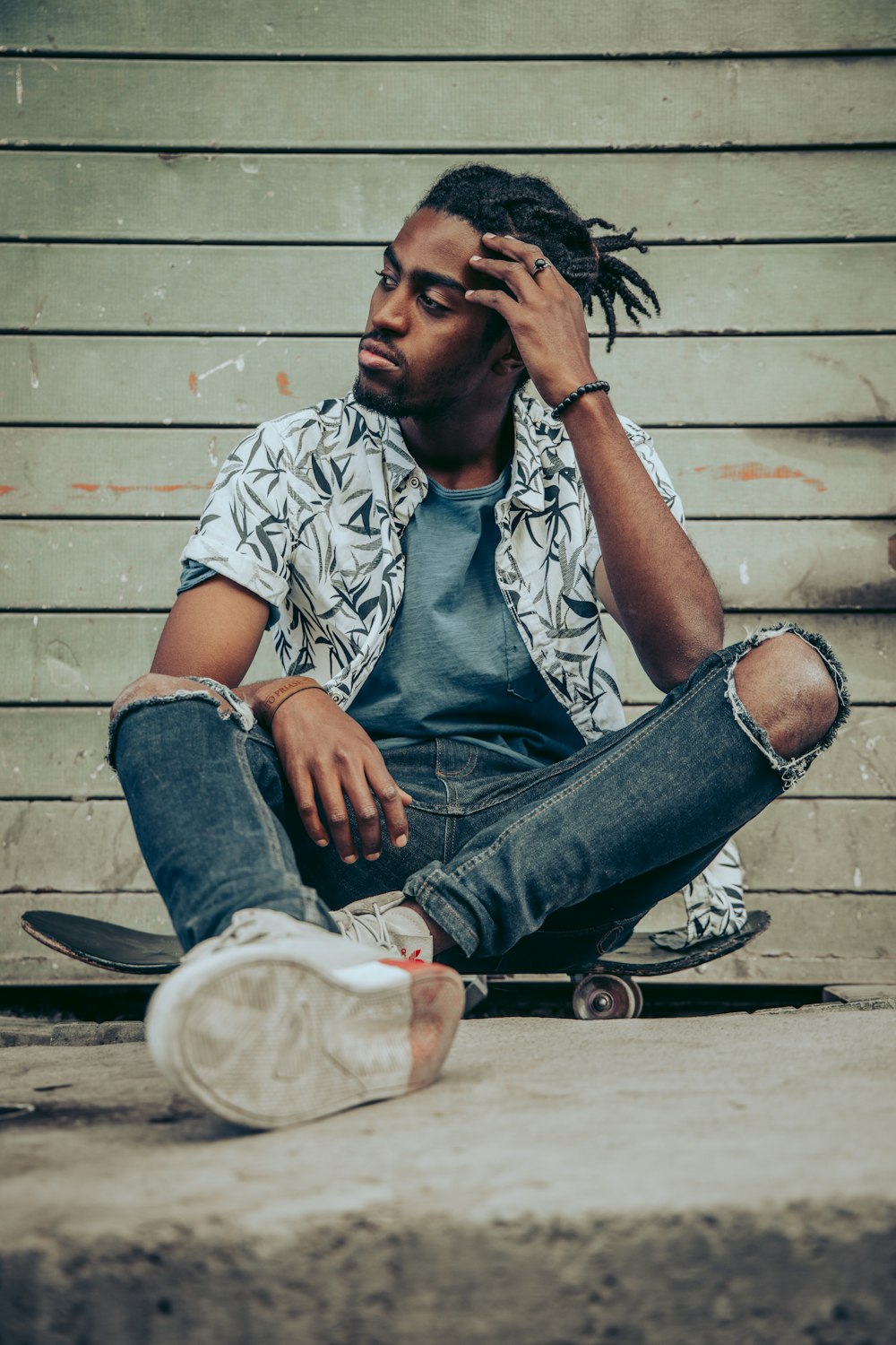 a man with dreadlocks sitting on the ground