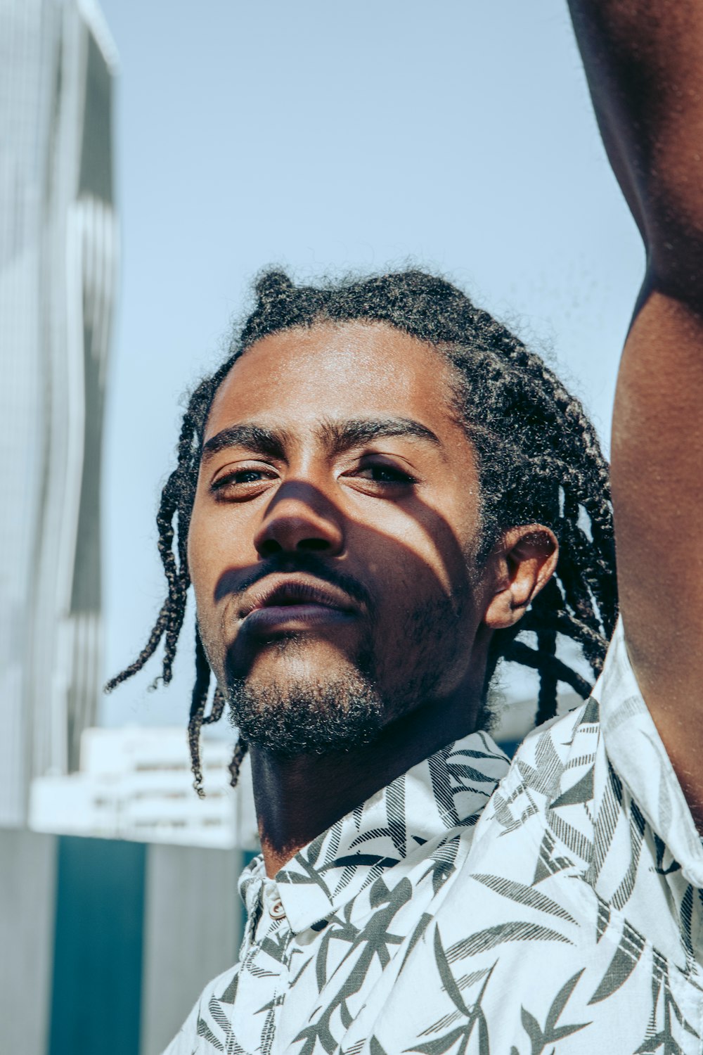 a man with dreadlocks standing in front of a building