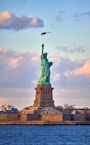 a plane flying over the statue of liberty