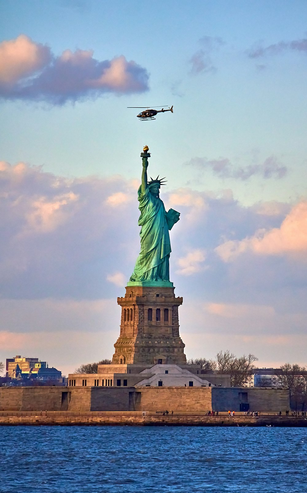 a plane flying over the statue of liberty