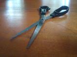 Close-up of sleek barber scissors resting on a wooden counter with soft natural light.