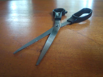 Close-up of sleek stainless steel scissors resting on a wooden table with soft natural light.