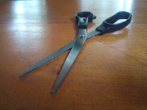 Matte gold scissors resting on deep emerald green fabric in soft natural light.