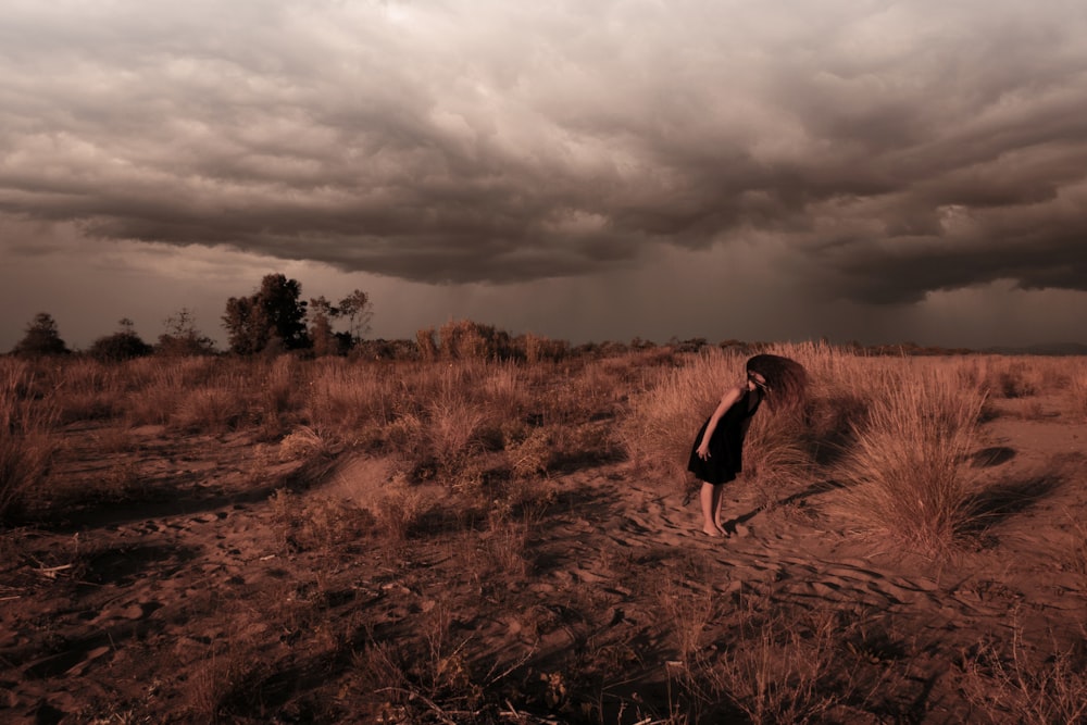 a person standing in a field under a cloudy sky