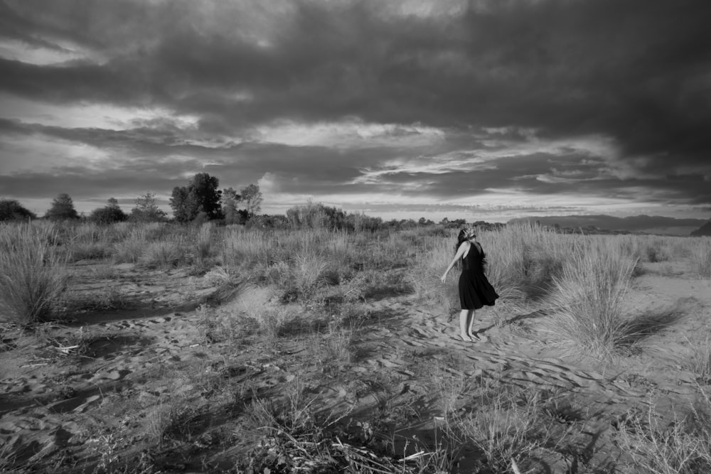 a black and white photo of a woman walking in a field