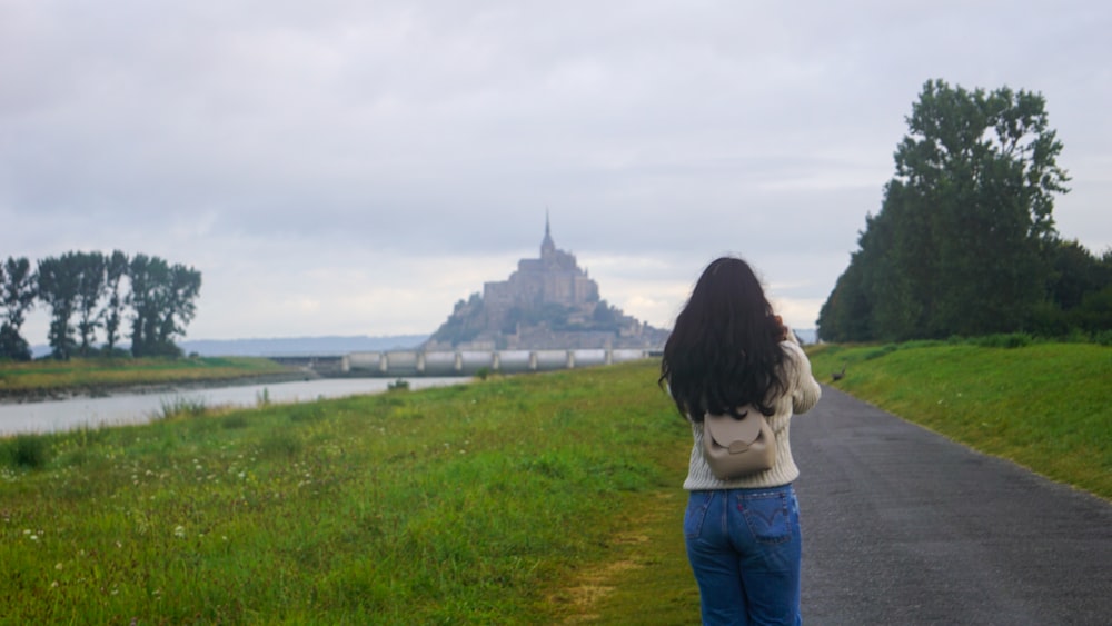 a woman taking a picture of a castle in the distance