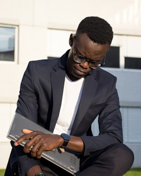 a man in a suit sitting on a bench using a laptop