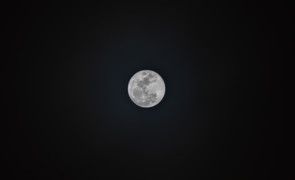 uma lua cheia é vista no céu escuro
