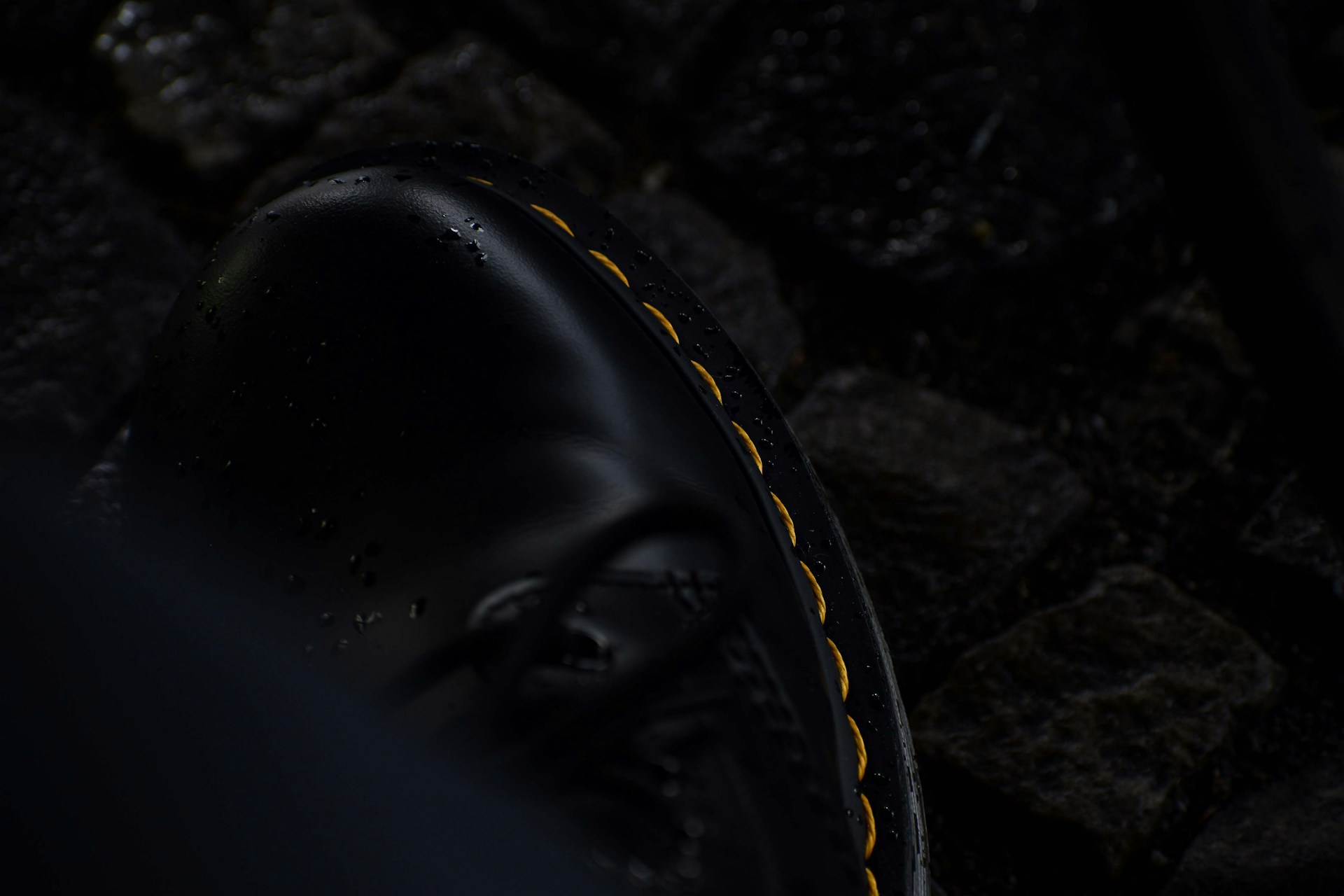 a close up of a black shoe with yellow stitchs