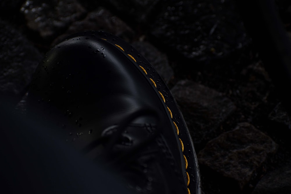 a close up of a black shoe with yellow stitchs