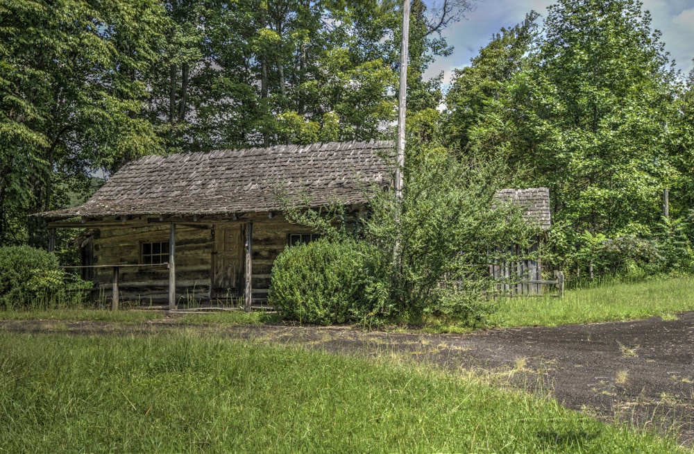 an old log cabin in the middle of a field