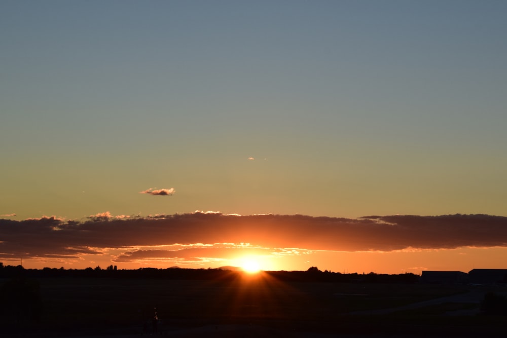 the sun is setting in the sky over a field