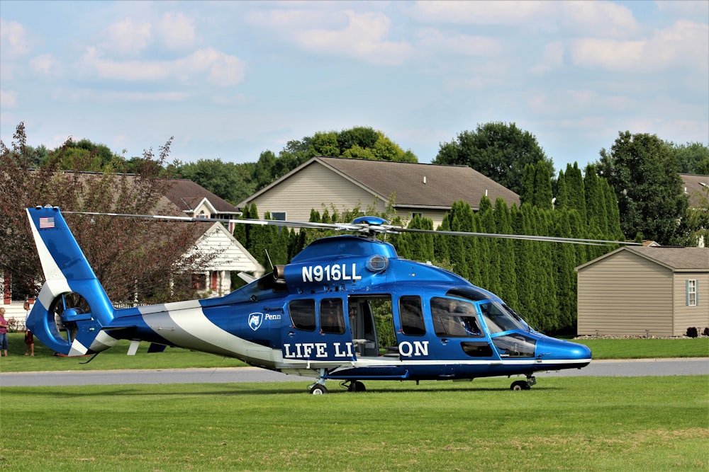 a blue and white helicopter sitting on top of a lush green field