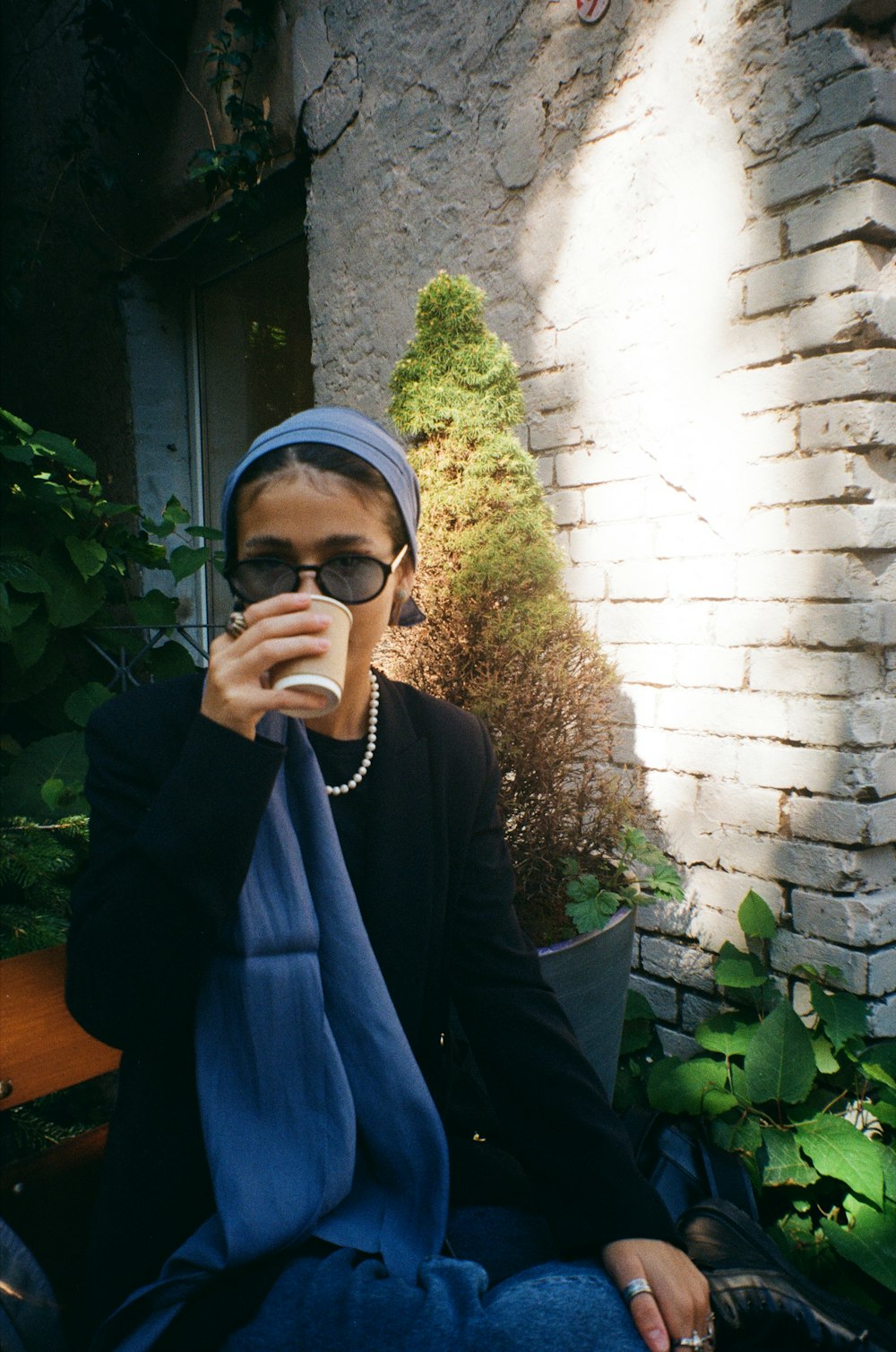 a woman sitting on a bench drinking from a cup