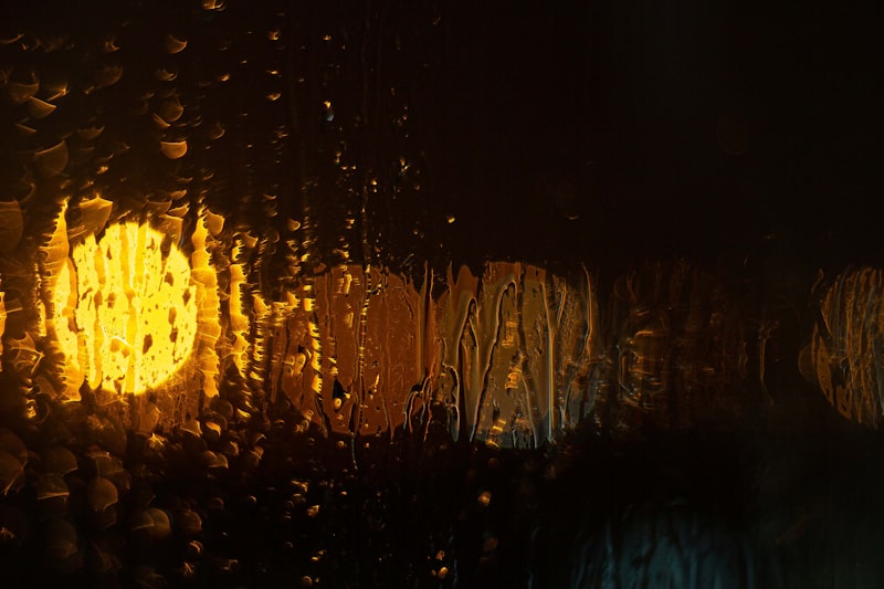 Raindrops on a window with a warm streetlight blurred behind