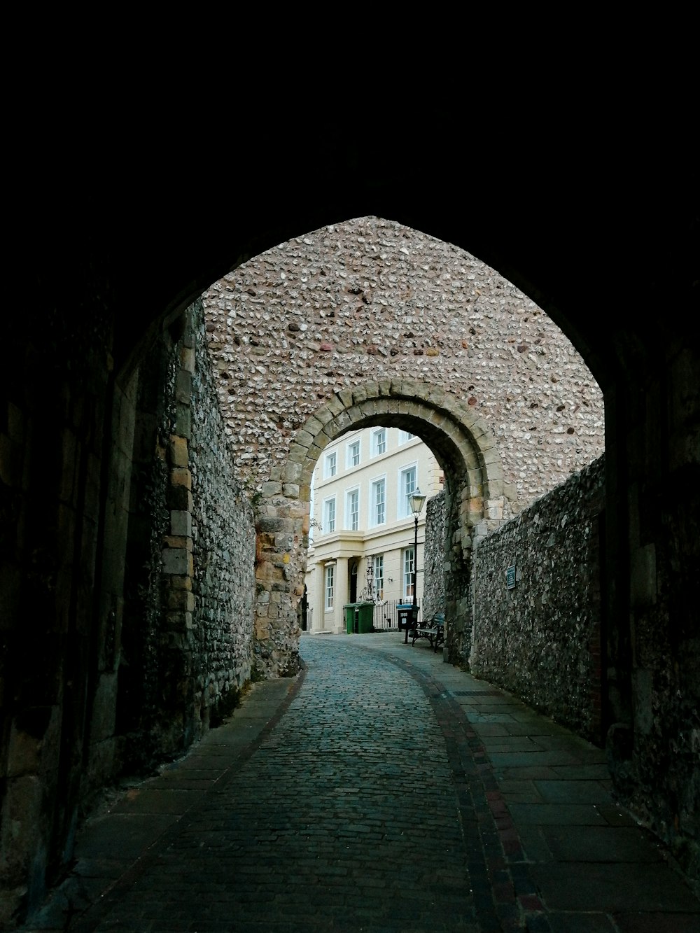 a stone archway leading to a building with a clock on it