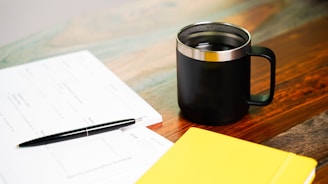 a cup of coffee and a pen on a table