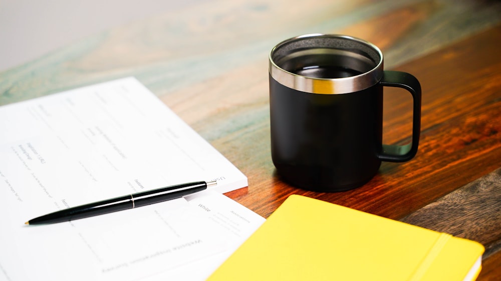 una tazza di caffè e una penna su un tavolo