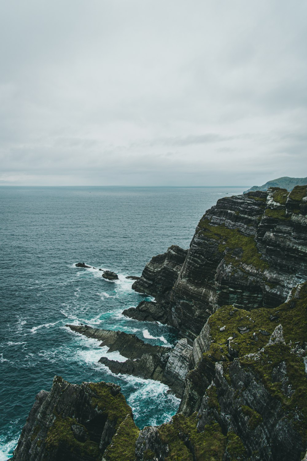 a rocky cliff overlooking the ocean on a cloudy day