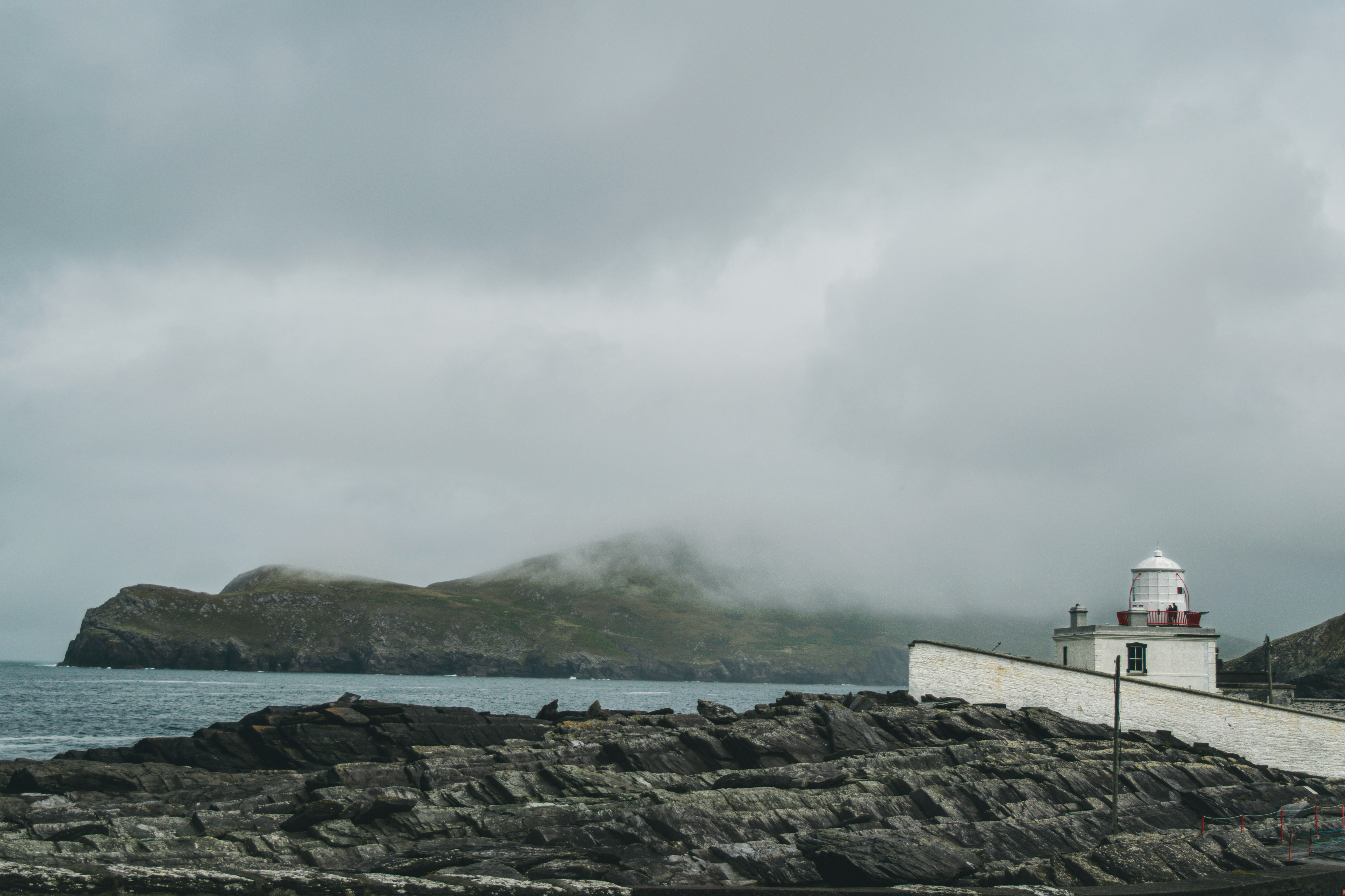 a lighthouse on a rocky shore on a cloudy day, 