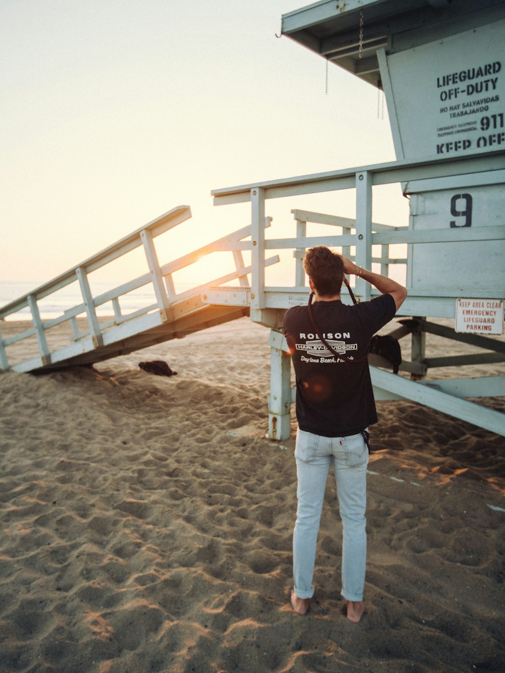 a man standing on a beach next to a lifeguard tower