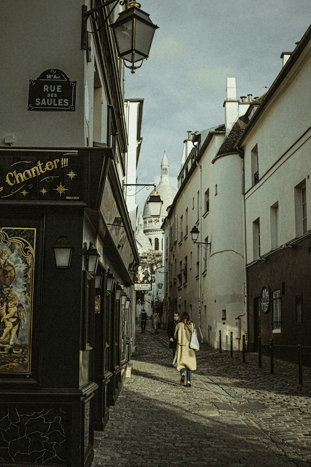 a woman walking down a street next to tall buildings